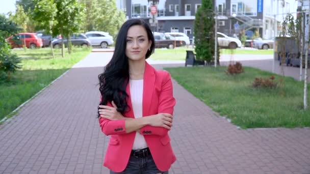 Een vrouw in een rood jasje in een stadspark op een heldere zonnige dag. — Stockvideo