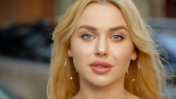 Porträtt av en blond med fulla läppar och blå ögon på en bakgrund av parkering — Stockvideo