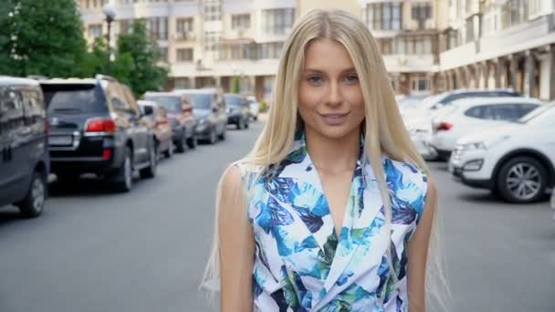 Blond in een zomerpak poserend op de parkeerplaats. Camera bedrading. Vrouwenwandeling — Stockvideo