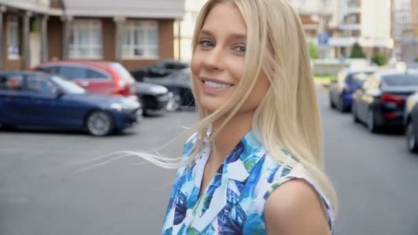 Блондинка в летнем костюме позирует на парковке. Проводка камеры. Женская прогулка — стоковое видео