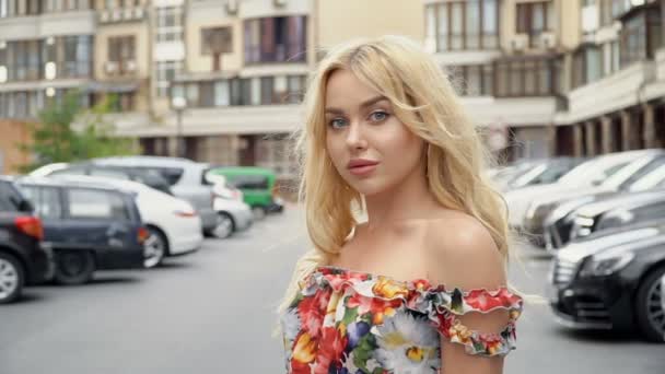 Portrait d'une blonde aux lèvres pleines et aux yeux bleus sur fond de parking — Video