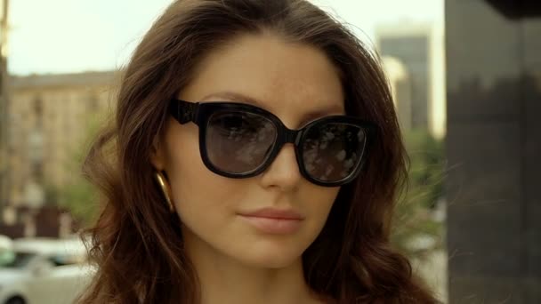 Portrét krásné moderní dívky s kulatými brýlemi ve městě. Sezónní styl, letní krása, móda. — Stock video
