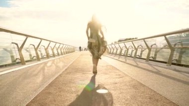 Şehirde köprüde yürüyen mutlu genç bir kadının portresi.