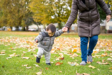 Bebeğin ilk adımları annesi ile parkta yürüyüş