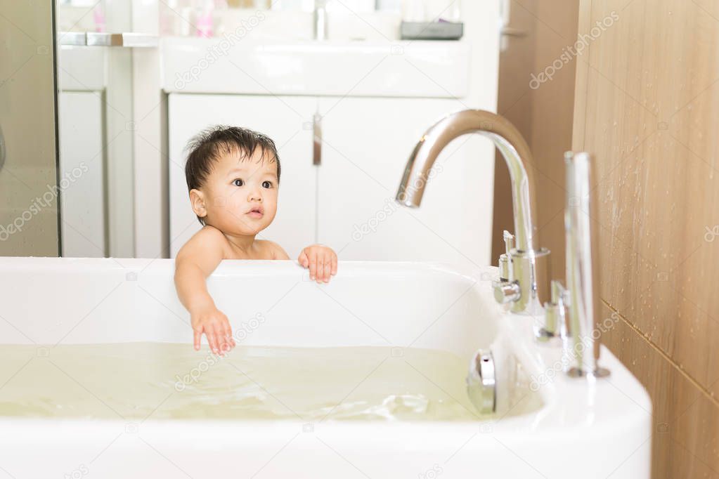 Asian kid in the bathroom with bathtub