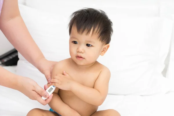 Mother uses the thermometer for Asian baby