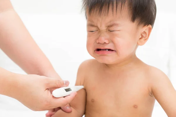 Mother uses the thermometer for Asian baby