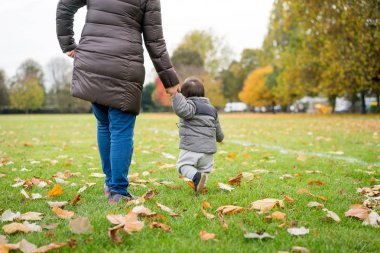 Bebeğin ilk adımları annesi ile parkta yürüyüş