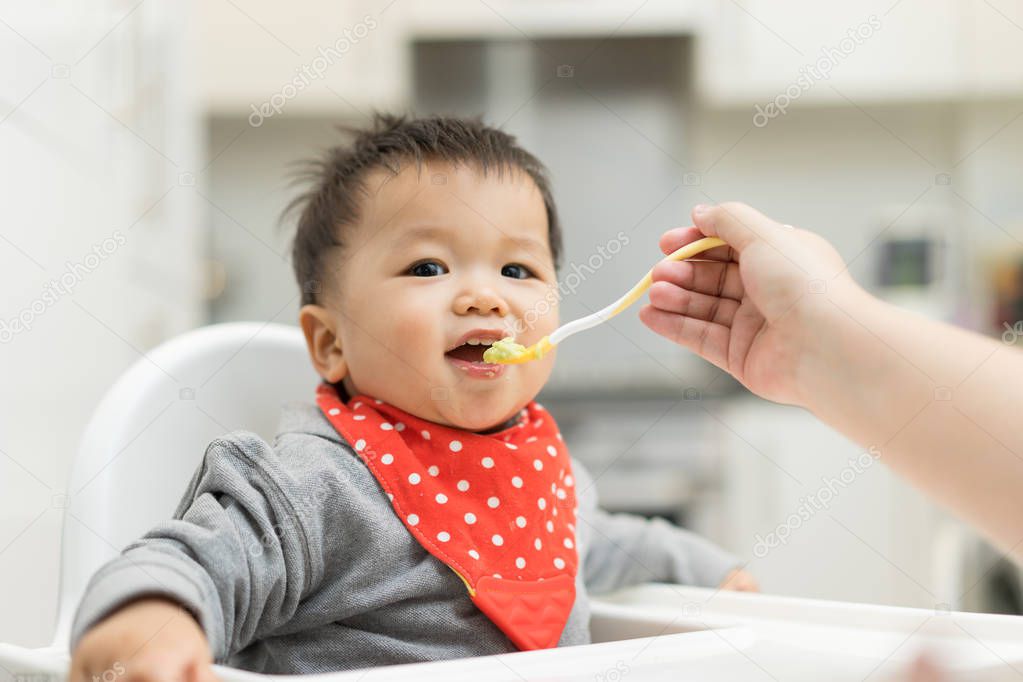 Asian baby boy eating blend food on a high chair