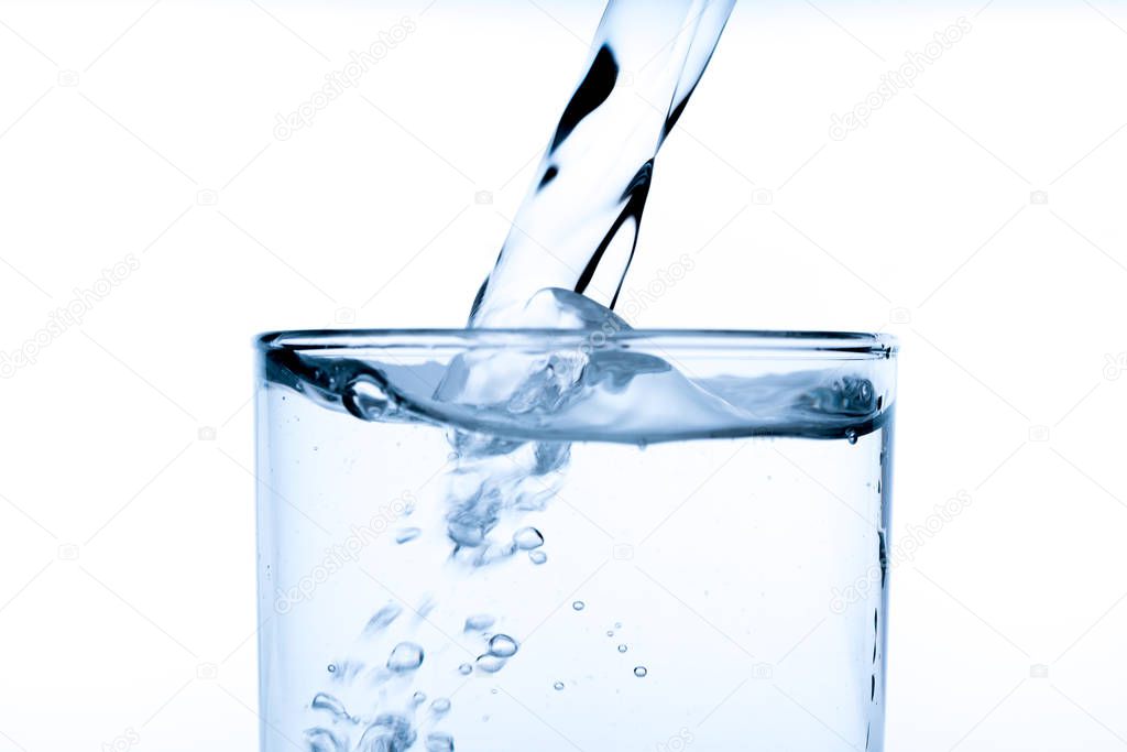 Glass of water with pouring from the bottle, studio shot