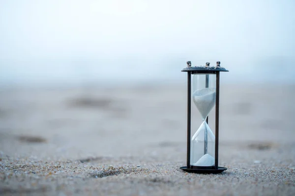 Sand clock on the beach, business time management concept