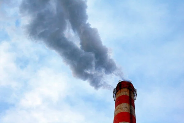 dense emissions into the atmosphere of industrial waste from the factory pipe, against the blue sky