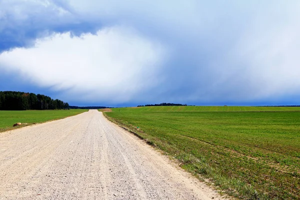 yağmur kara bulutlar Avrupa'da kırsal, tarla, çakıl yol üzerinde asılı önce, yeşil bir alanın ortasında