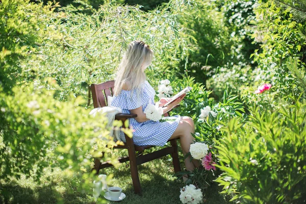 若い女性はお茶のマグと椅子に庭で休憩します — ストック写真