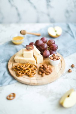 Peynir tabağı ile üzüm, bal, kraker ve fındık ahşap bir tabakta servis