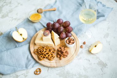Peynir tabağı ile üzüm, bal, kraker ve fındık ahşap bir tabakta servis