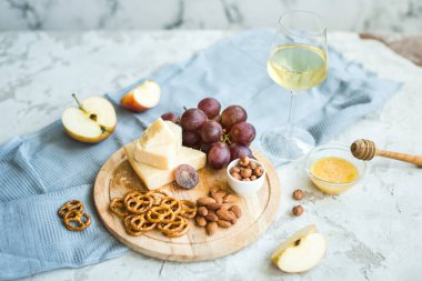 Peynir tabağı ile üzüm, bal, kraker ve fındık ahşap bir tabakta servis