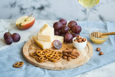 Peynir tabağı ile üzüm, bal, kraker ve fındık ahşap bir tabakta servis