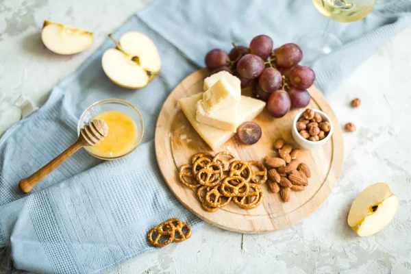 Peynir tabağı ile üzüm, bal, kraker ve fındık ahşap bir tabakta servis