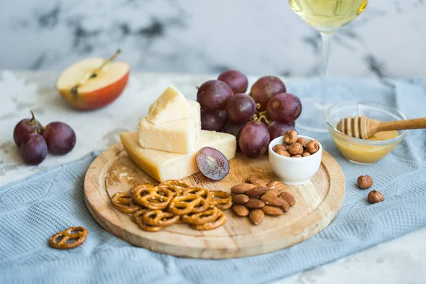 Peynir tabağı ile üzüm, bal, kraker ve fındık ahşap bir tabakta servis