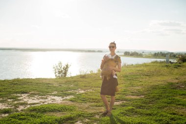 küçük bir çocuk annesi, askı içinde oturuyor