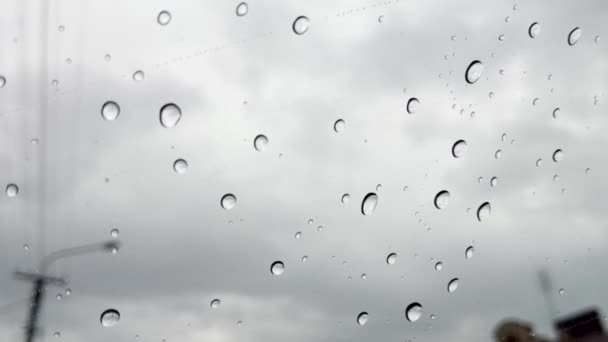 Druppels regen op een venster met een grijze lucht achter — Stockvideo