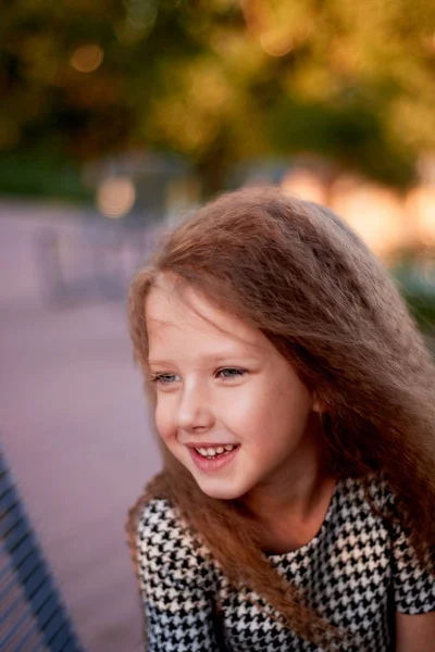 Barnet är 4 år gammal, med blå ögon och små lockar. Barnens glädje av liv och äventyr. Varma gyllene solnedgången ljus. Leenden — Stockfoto