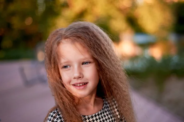 El bebé tiene 4 años, ojos azules y rizos pequeños. Los niños disfrutan de la vida y las aventuras. Cálida luz dorada al atardecer. Sonrisas. — Foto de Stock