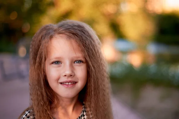 El bebé tiene 4 años, ojos azules y rizos pequeños. Los niños disfrutan de la vida y las aventuras. Cálida luz dorada al atardecer. Sonrisas. —  Fotos de Stock