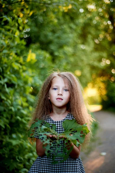 Bebé de 4 años, con ojos azules, rizos pequeños. Un tiempo maravilloso de la infancia y la aventura.La cálida luz del sol Derita en las manos de la taza con fugas . —  Fotos de Stock