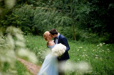 Gelin ve damat beyaz alanıyla yol boyunca yürümek. Park veya orman. Düğün yürüyüş ve fotoğraf ateş