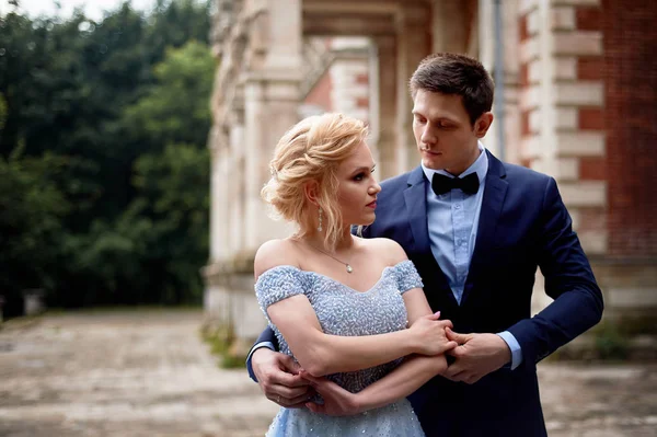 The bride and groom dancing around the columns of the old estate. A tall groom, and a bride with blond hair. Blue wedding dress.Wedding walk and photo shoot