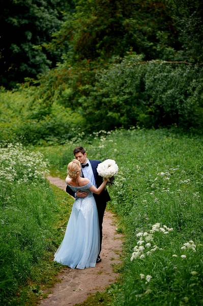 Gelin ve damat beyaz alanıyla yol boyunca yürümek. Park veya orman. Düğün yürüyüş ve fotoğraf ateş — Stok fotoğraf