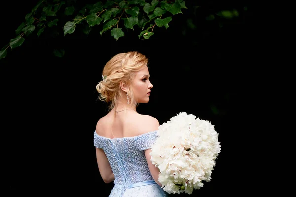 Bruden i naturen, med en stor bukett av pioner. I en blå, broderad klänning. Bröllop promenad, Foto shoot — Stockfoto