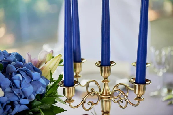 Tablo klasik bir tasarıma sahip. Vazoda bir yüksek ortancaları ve lilyum, Altın şamdan mavi mum ile bir kompozisyon ile. Dekor ve floristik