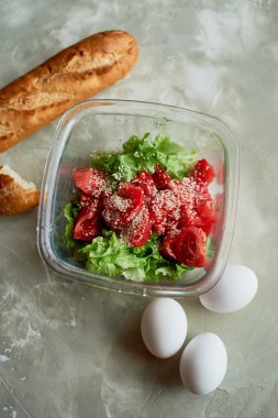 Basit, lezzetli ve besleyici bir yemek. Taze domates salatası, baget ve haşlanmış yumurta. Gri bir arka plan üzerinde beton altında