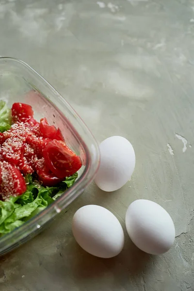 Köstliche, einfache und nahrhafte Mahlzeit. frischer Tomatensalat und gekochte Eier auf grauem Grund unter Beton — Stockfoto