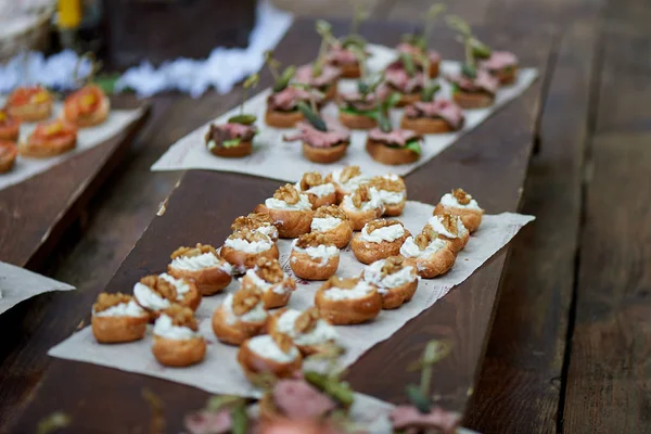 Catering för bröllop Banquet.Canapes, små smörgåsar på papper och trä yta — Stockfoto
