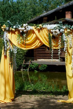 Arch Sarı kumaş ve çiçeklerle süslenmiş açık havada düğün töreni için. Ayrıntılar kapatın