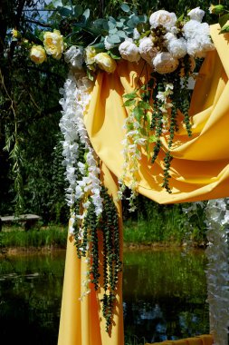 Arch Sarı kumaş ve çiçeklerle süslenmiş açık havada düğün töreni için. Ayrıntılar kapatın