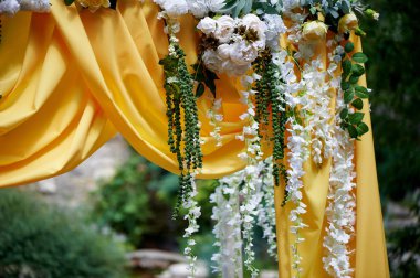 Arch Sarı kumaş ve çiçeklerle süslenmiş açık havada düğün töreni için. Ayrıntılar kapatın