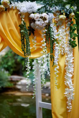 Arch Sarı kumaş ve çiçeklerle süslenmiş açık havada düğün töreni için. Ayrıntılar kapatın