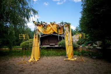 Arch Sarı kumaş ve çiçeklerle süslenmiş açık havada düğün töreni için.