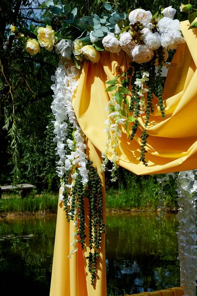 Arch Sarı kumaş ve çiçeklerle süslenmiş açık havada düğün töreni için. Ayrıntılar kapatın