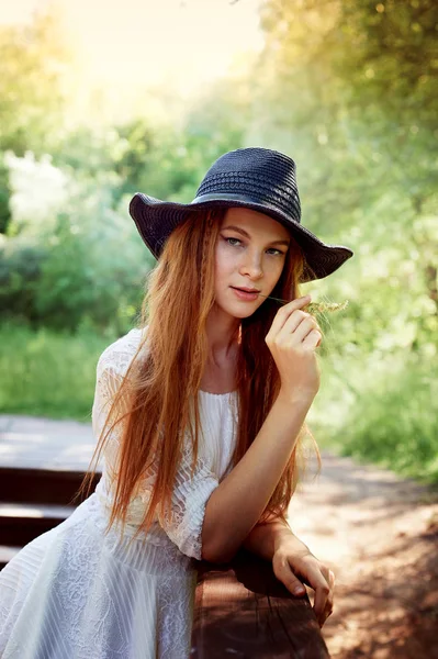 Портрет рудоволоса дівчина з довгим волоссям, в чорному широко розмальованому капелюсі. Тепле сонячне світло — стокове фото
