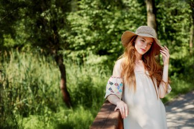 Sofistike Kızıl saçlı elbiseli bir kız bir basit keten, şapkalı bir ışık geniş ekledi. Model bak. Doğal güzellik. Sanatsal portre