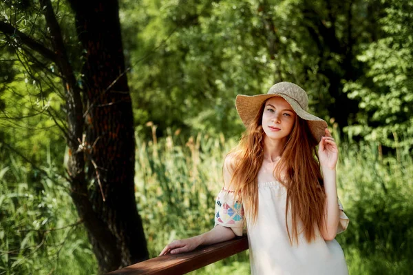 Una chica de pelo rojo sofisticado en un vestido de lino simple, con un sombrero de ala ancha luz. Belleza natural. Retrato artístico —  Fotos de Stock