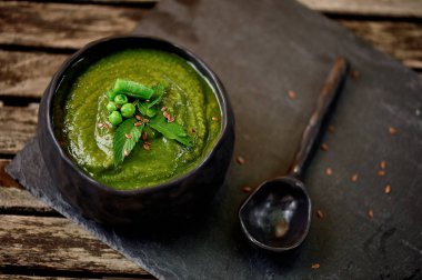 Yeşil brokoli çorbası, gri bir stand ve bir ahşap arka plan. Rustik tarzı. Basit, besleyici vejetaryen yemek. Tohum ile dekore edilmiş