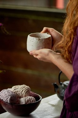 Bir büyük kil kupa çay ile tutarak mor elbiseli Kızıl saçlı kız. Temiz hava çay. Hayattan zevk