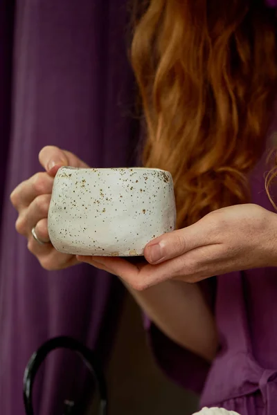 Menina de cabelos vermelhos em um vestido roxo segurando uma caneca de barro maciço com chá.Chá no ar fresco. Aproveite a vida — Fotografia de Stock